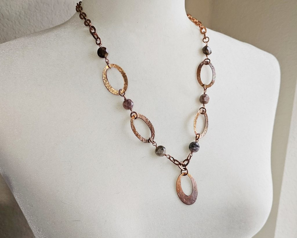 Necklace made with copper oval washers alternating faceted petrified wood coin beads, and an oval copper pendant.