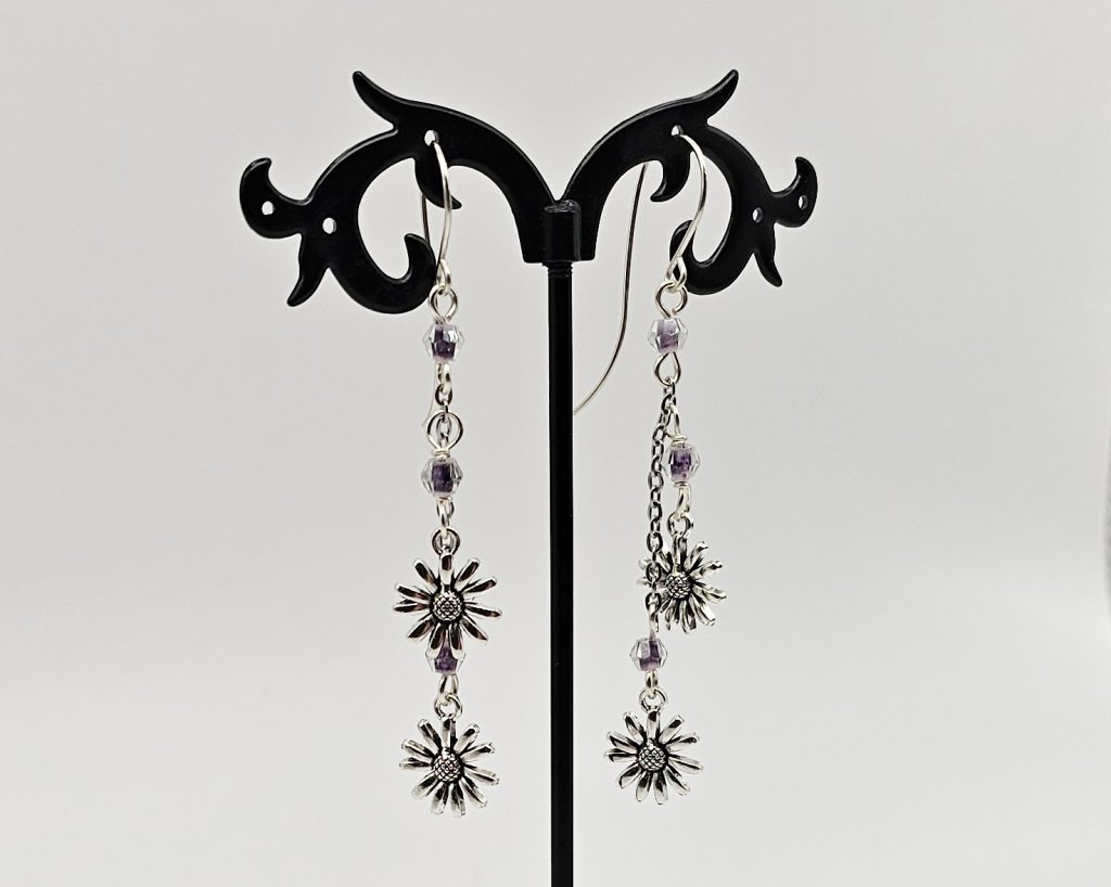 Handmade 2.5 inch dangle earrings with violet swirl crystal beads and silver daisy flower charms on delicate chains.