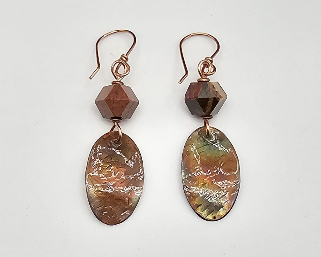 Handmade earrings with a copper oval dangle, hammered and flame colored, hung with diamond cut mookaite bead on copper earring wires