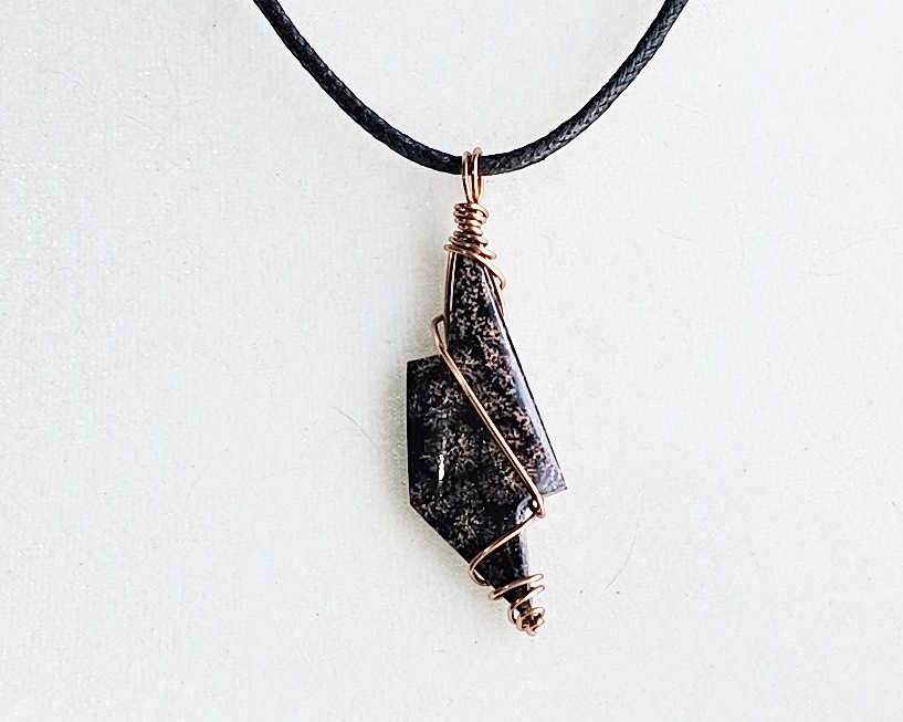 Handmade obsidian pendant necklace wrapped in copper wire on a black waxed cotton cord with a geometric stone design.