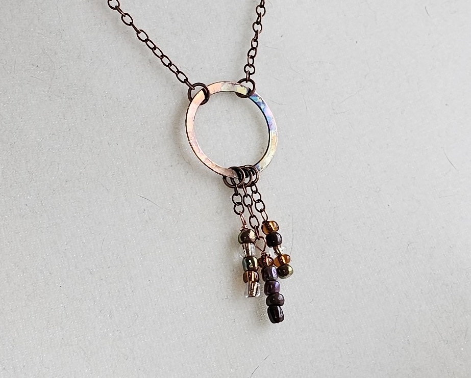 Handmade flame-colored copper circle necklace with glass seed bead dangles on a 20-inch copper chain with hook clasp.