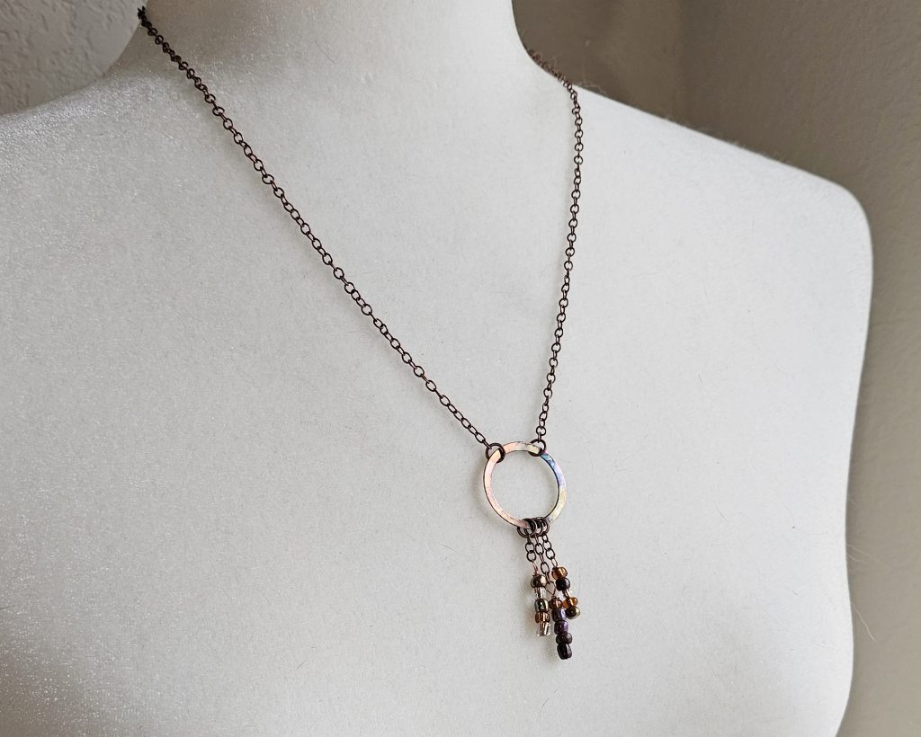 Handmade flame-colored copper circle necklace with glass seed bead dangles on a 20-inch copper chain with hook clasp.