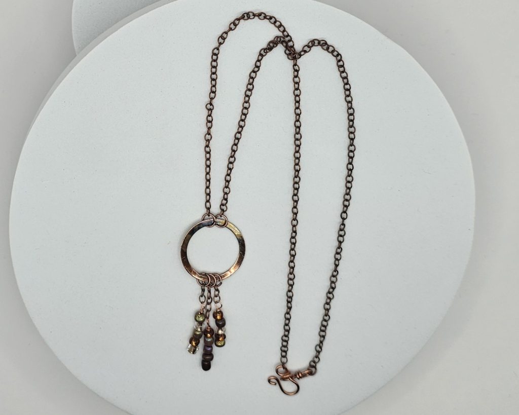 Handmade flame-colored copper circle necklace with glass seed bead dangles on a 20-inch copper chain with hook clasp.