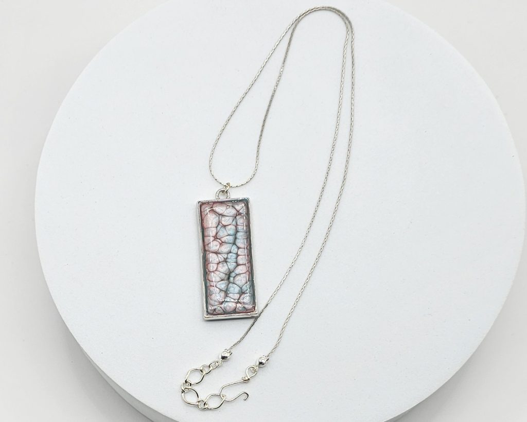 Handmade painted resin pendant necklace with pink and blue textured design on a silver-tone 20-inch snake chain.