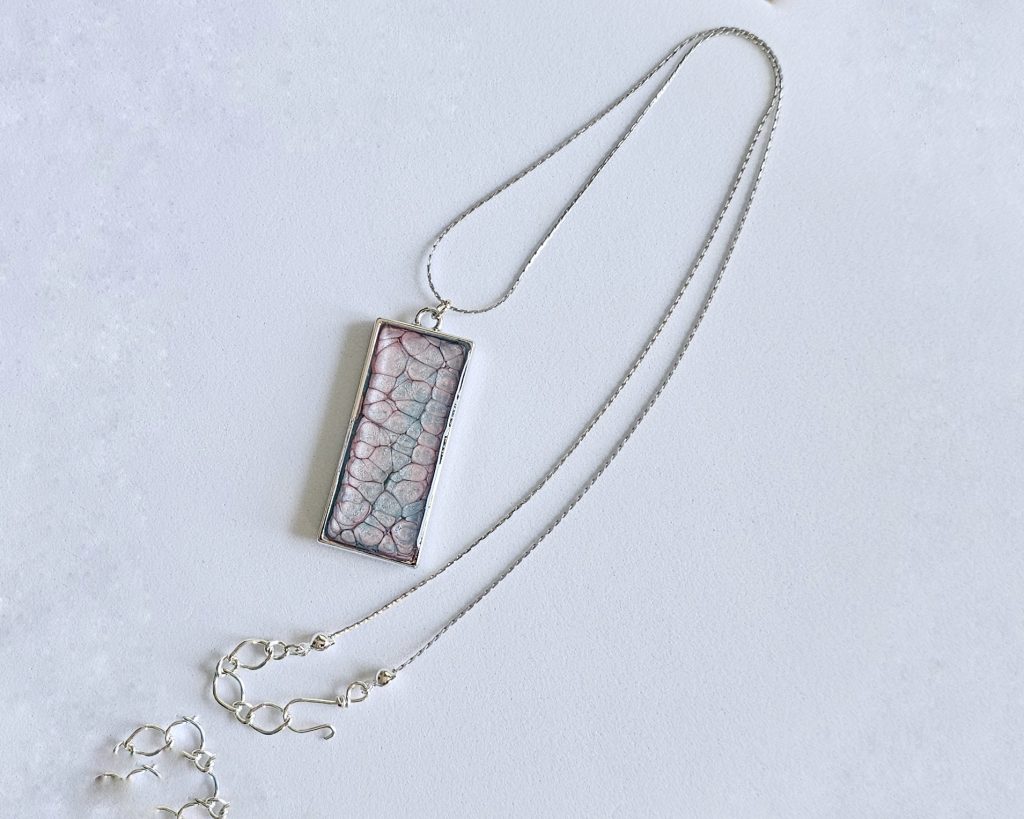 Handmade painted resin pendant necklace with pink and blue textured design on a silver-tone 20-inch snake chain.