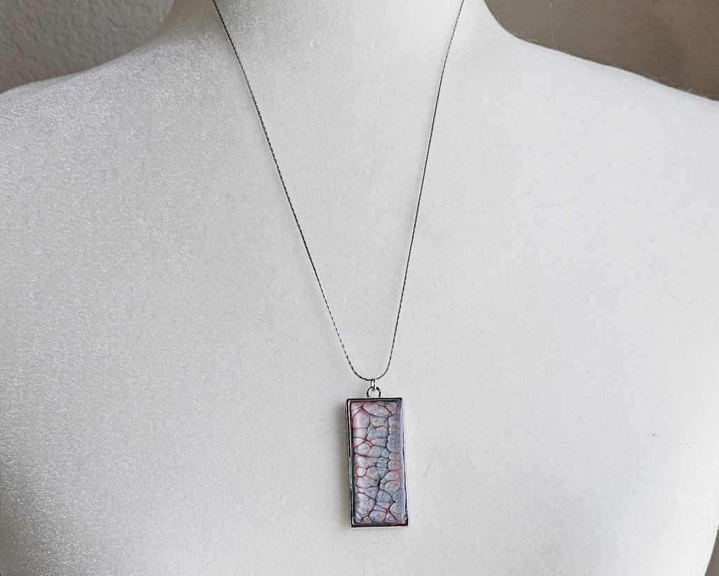 Handmade painted resin pendant necklace with pink and blue textured design on a silver-tone 20-inch snake chain.