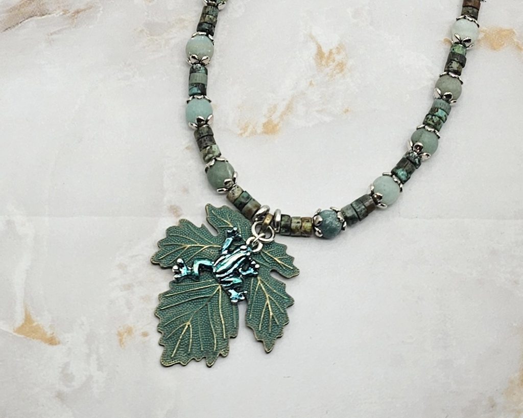 Handmade African turquoise jasper and amazonite necklace with antique bronze leaf pendant and hand-colored antique silver frog charm.