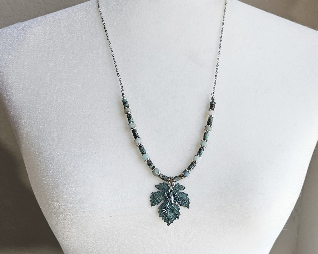 Handmade African turquoise jasper and amazonite necklace with antique bronze leaf pendant and hand-colored antique silver frog charm.