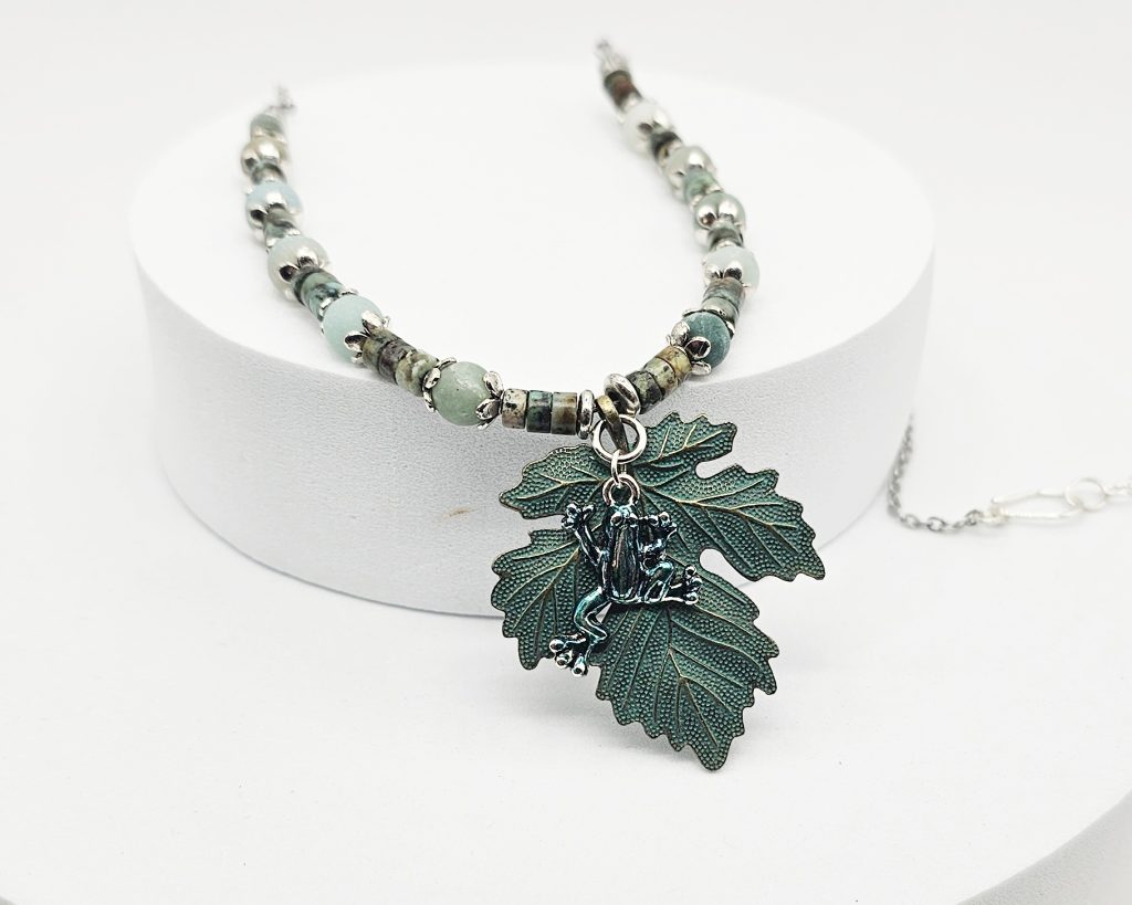 Handmade African turquoise jasper and amazonite necklace with antique bronze leaf pendant and hand-colored antique silver frog charm.
