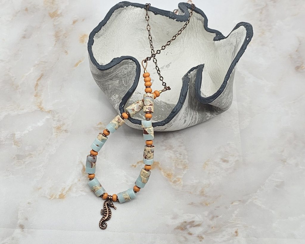 Handmade 19-inch necklace with impression jasper beads, orange glass accents, copper spacers, and a copper seahorse charm.