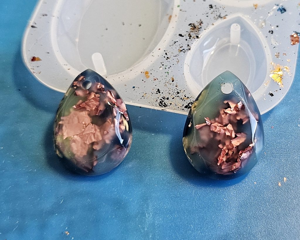 Teardrop shaped dangle made using UV resin and foil flakes in pink and gold, designed to mimic dichroic glass.